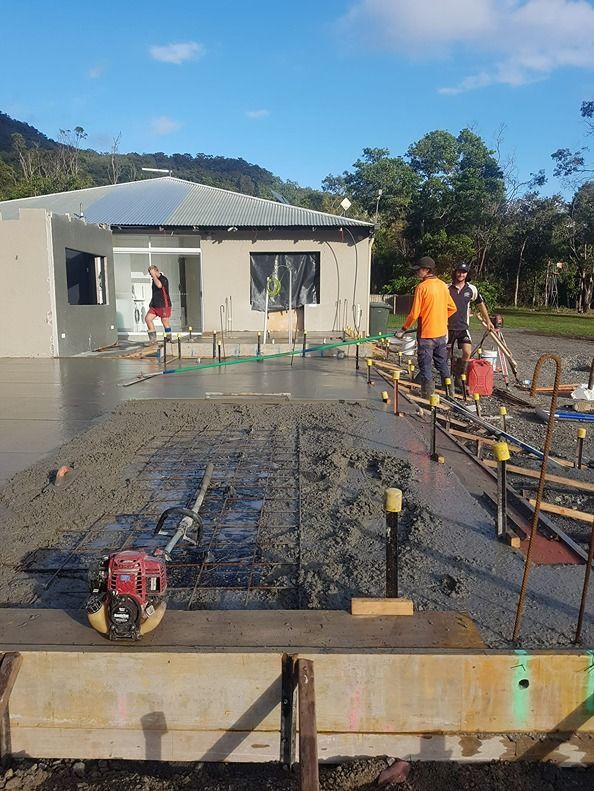 A Group Of Construction Workers Are Working On A Concrete Driveway — B & C Donnachie Concrete Contractors in Kuranda, QLD