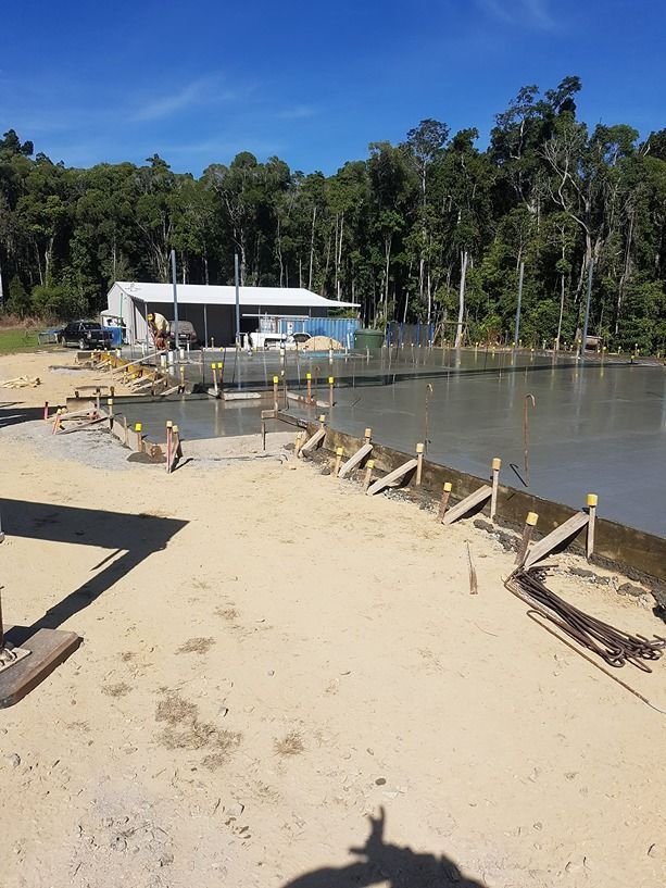 A Sandy Beach Next To A Body Of Water — B & C Donnachie Concrete Contractors in Kuranda, QLD