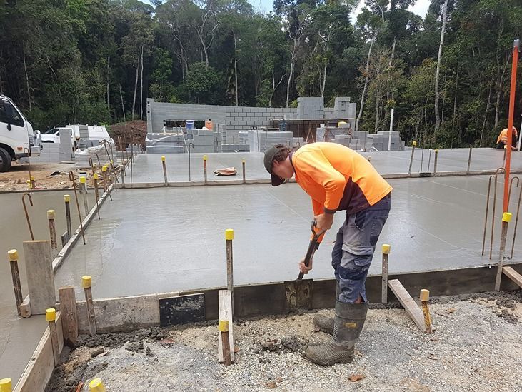 A Man Is Working On A Concrete Floor With A Shovel — B & C Donnachie Concrete Contractors in Kuranda, QLD