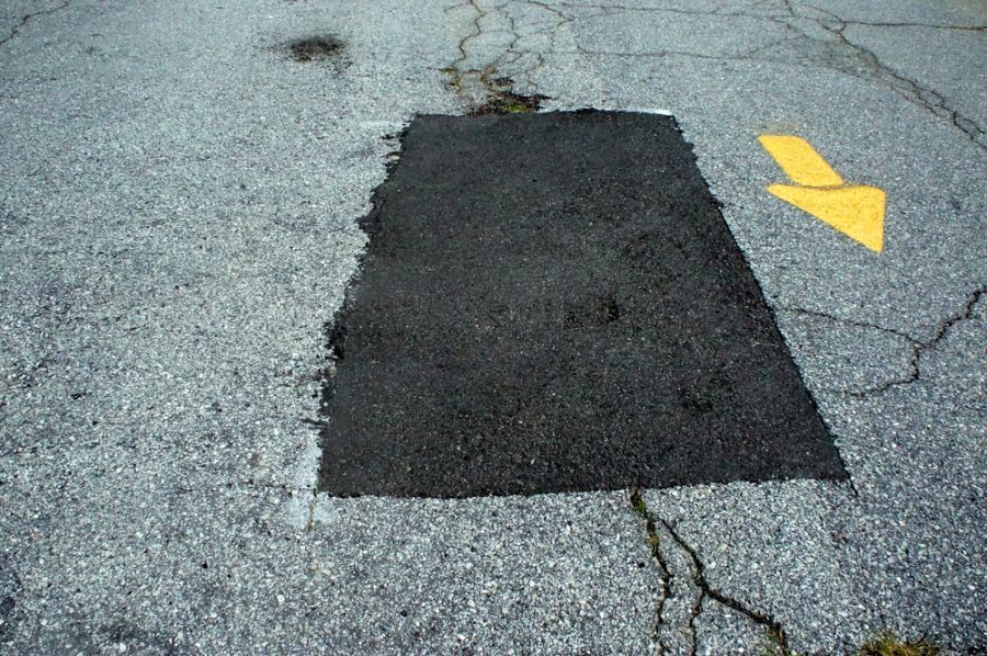 A Patch Of Asphalt With A Yellow Arrow Painted On It — B & C Donnachie Concrete Contractors in Smithfield, QLD