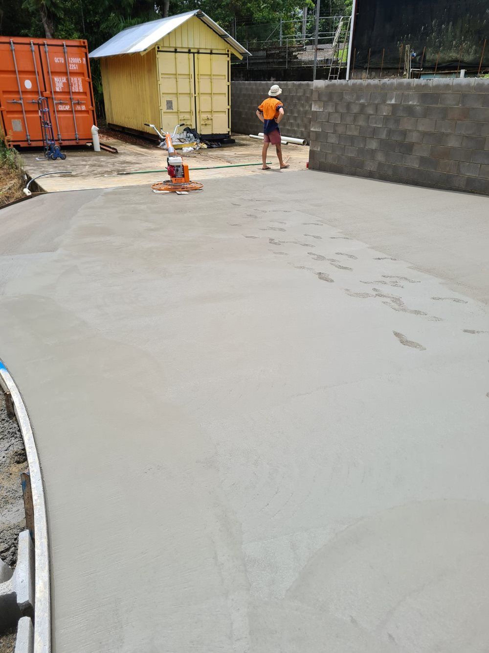 A Man Is Standing On A Concrete Surface In A Parking Lot — B & C Donnachie Concrete Contractors in Mareeba, QLD