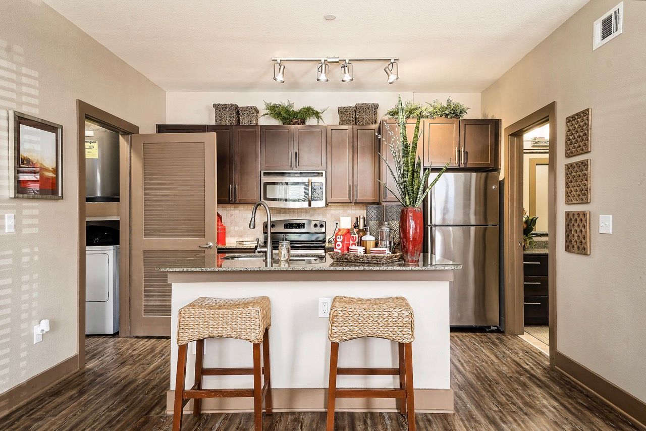 Kitchen in an apartment with dark wood cabinets, stainless steel appliances, and a breakfast island.
