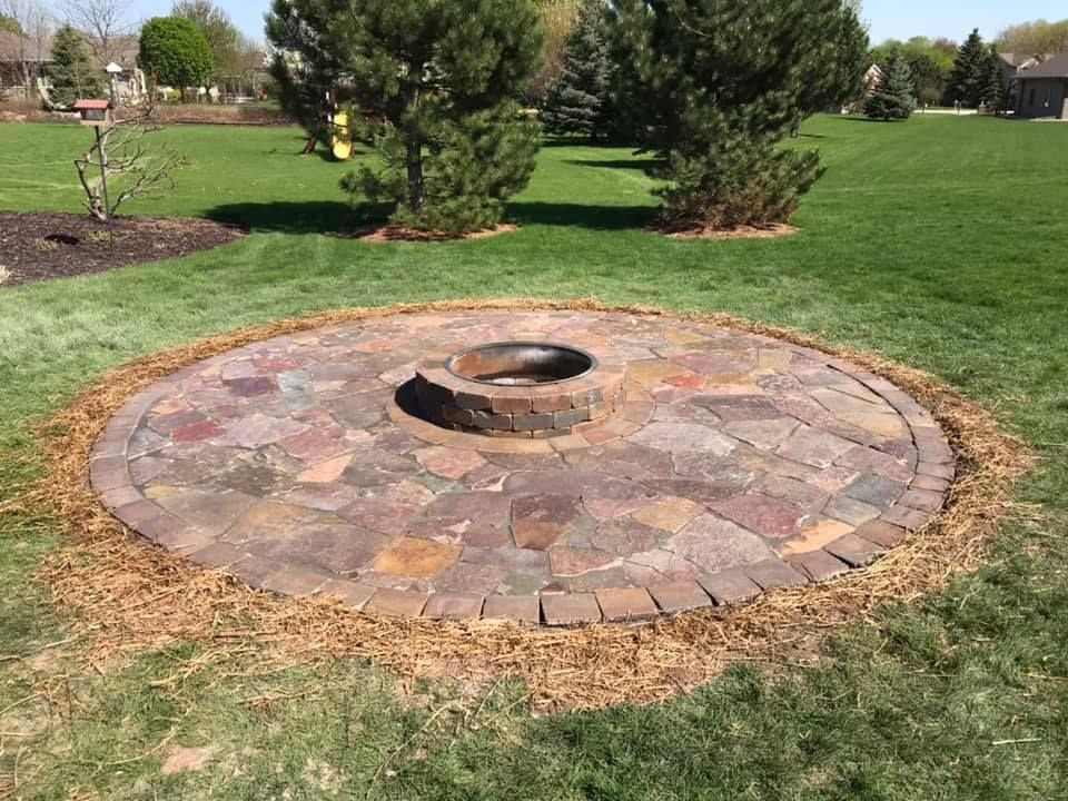 A Fire Pit Is Sitting In The Middle Of A Lush Green Field — Menasha, WI — Artscapes COC