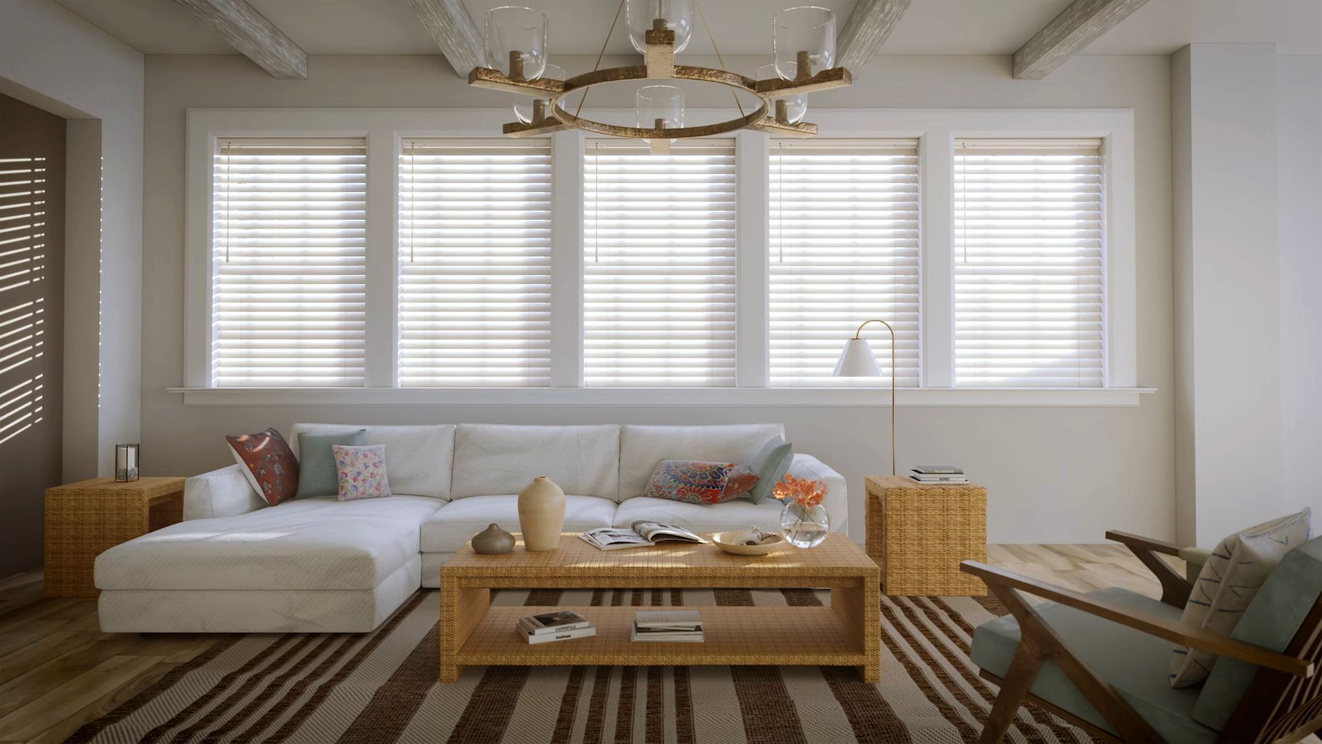 Living room with white sectional sofa, woven coffee table, and large windows with blinds.