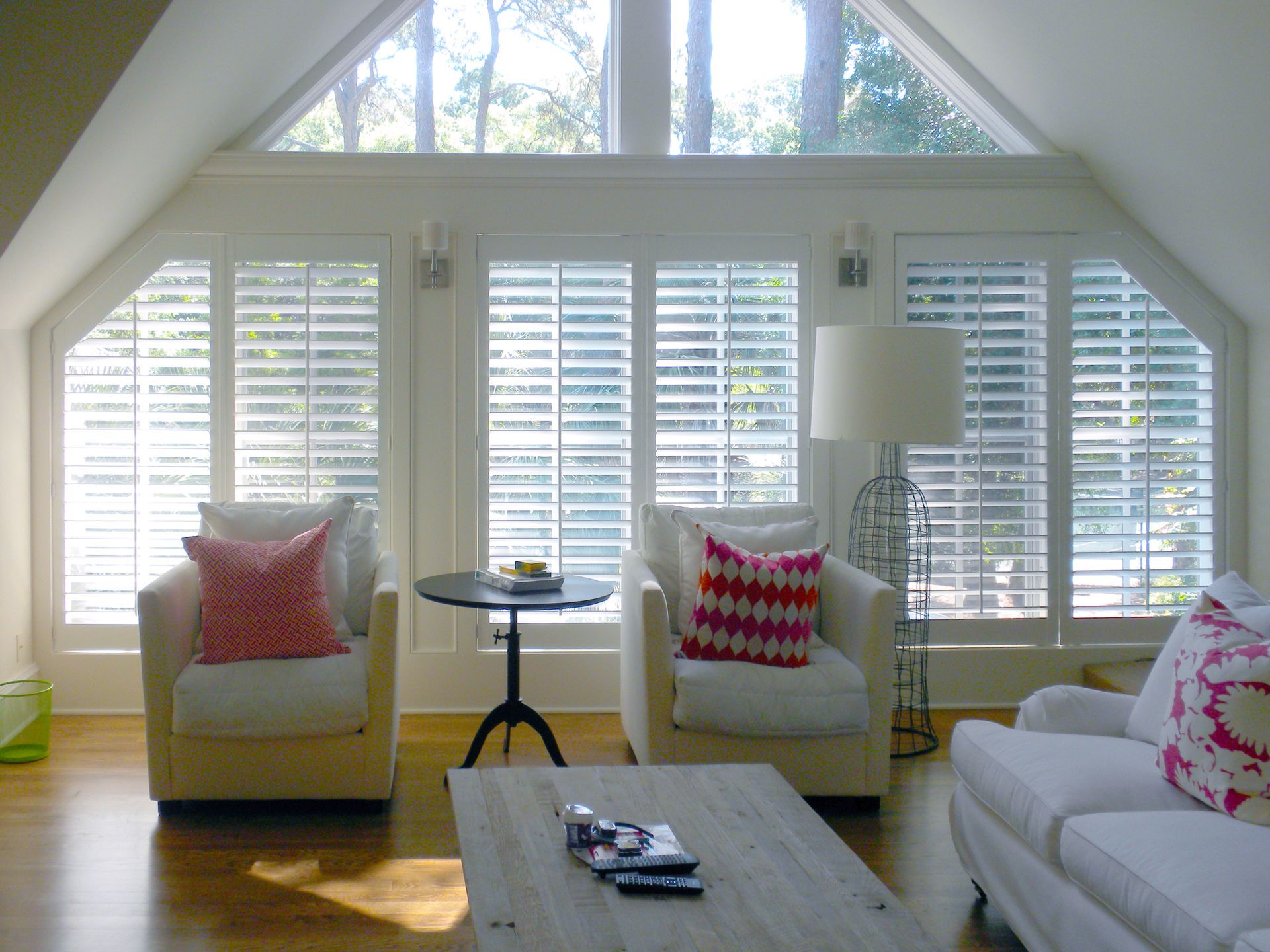 Bright living room with white shutters, armchairs, and a sofa.