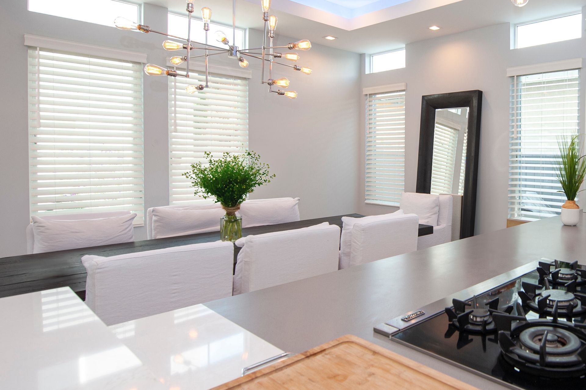 Modern dining room with a long table, white chairs, and large mirror.