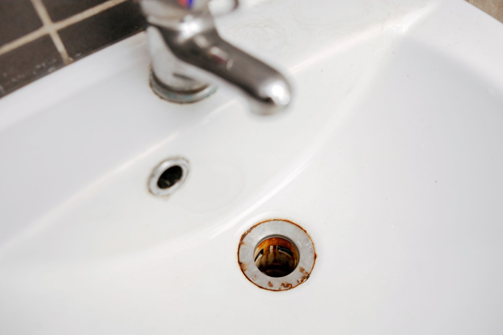 A close up of a bathroom sink with a faucet and drain.