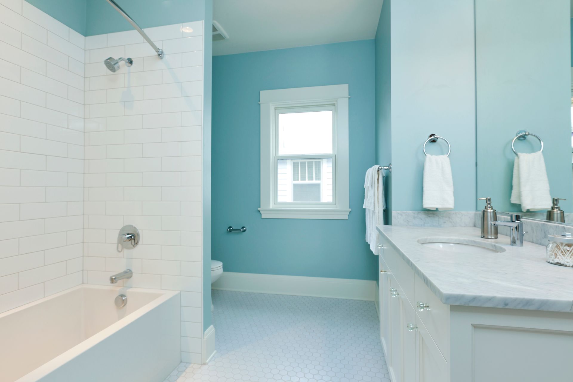 A bathroom with blue walls and white cabinets