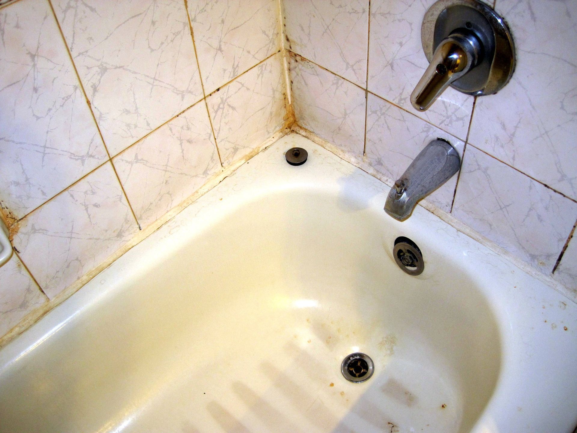 A bathtub with a faucet and drain in a bathroom.