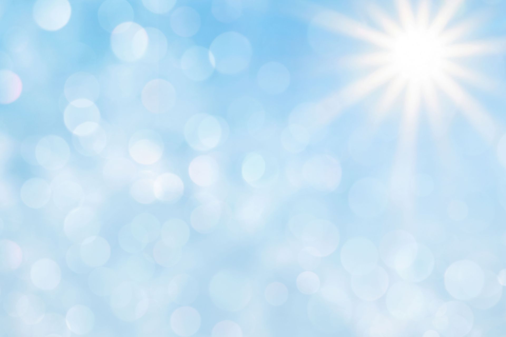 Bright blue sky with shining sun and bokeh effect.