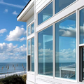 Modern white beachfront house with large windows overlooking the ocean and blue sky