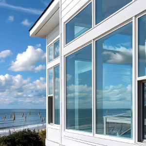 Modern white beachfront house with large windows overlooking the ocean and blue sky