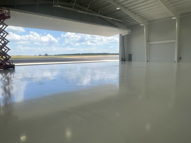 Woman in straw hat smiles, holding wine glass near a lake.