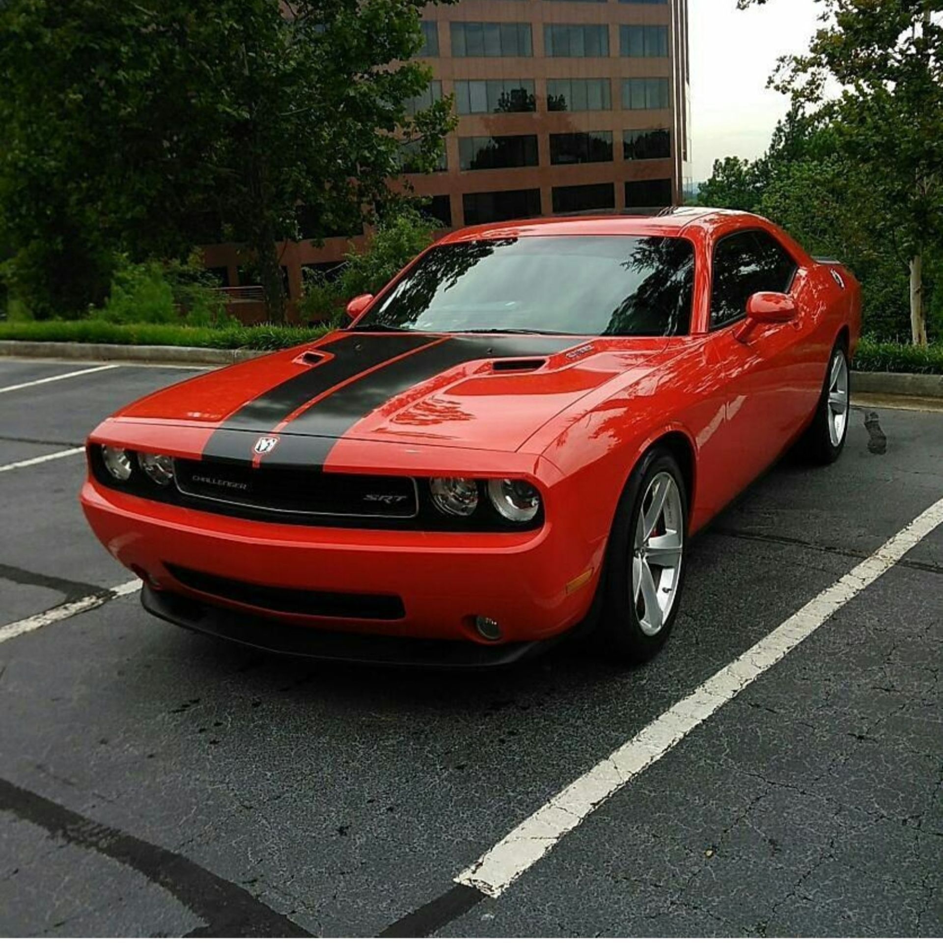 A red dodge challenger is parked in a parking lot