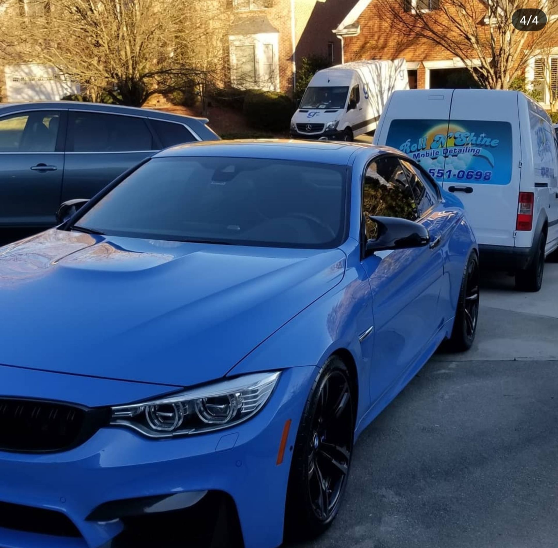A blue car is parked next to a white van that says auto shine