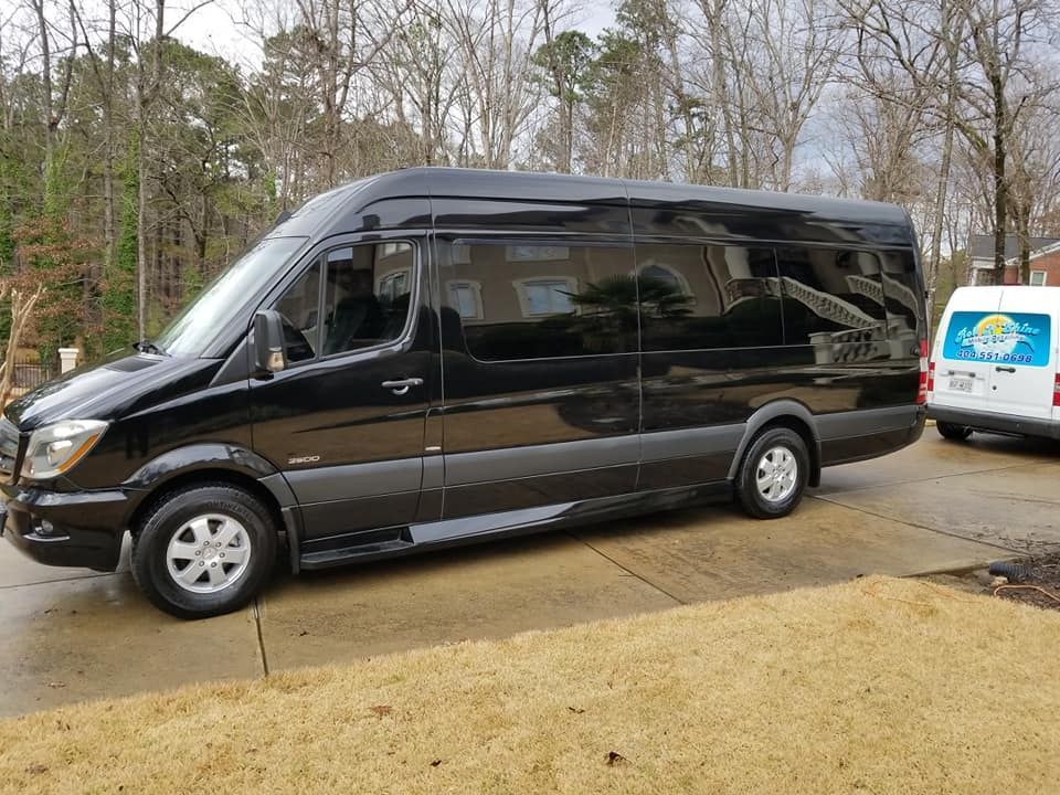 A black van is parked in a driveway next to a white van.