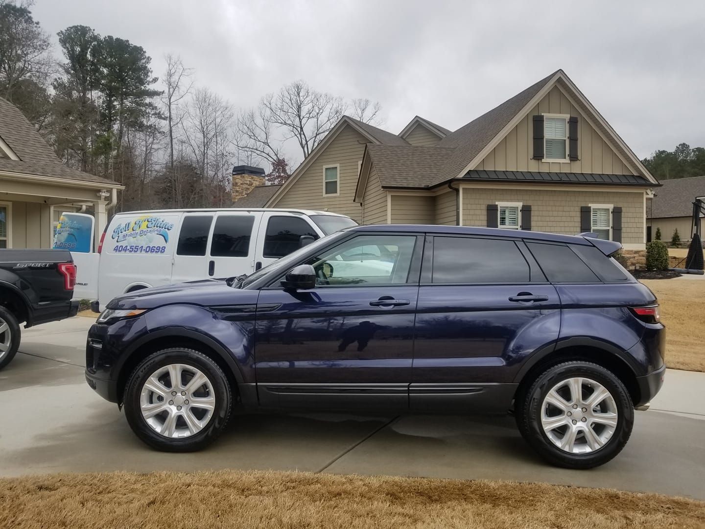 A blue range rover is parked in front of a house.
