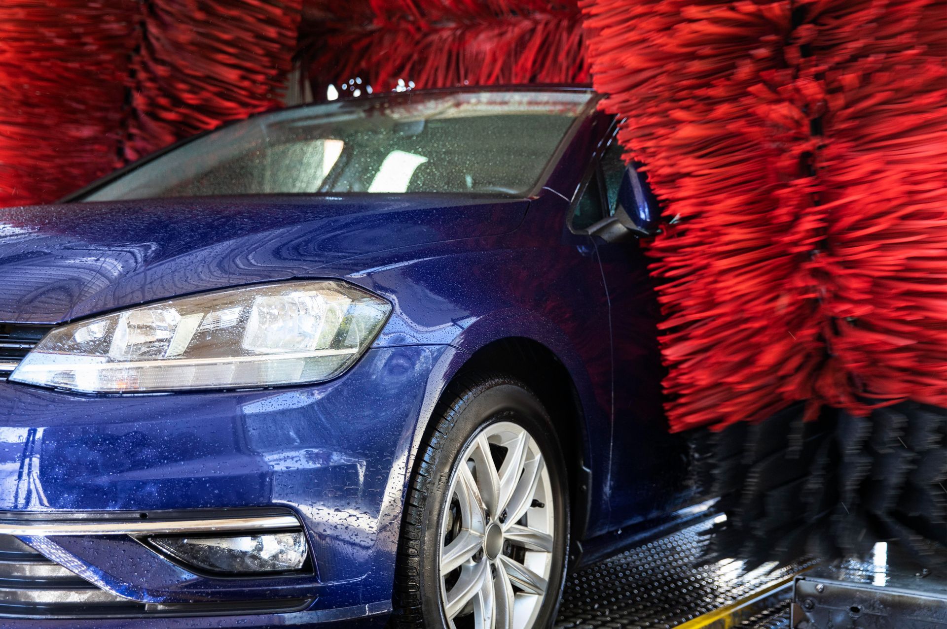 A blue car is being washed in a car wash.