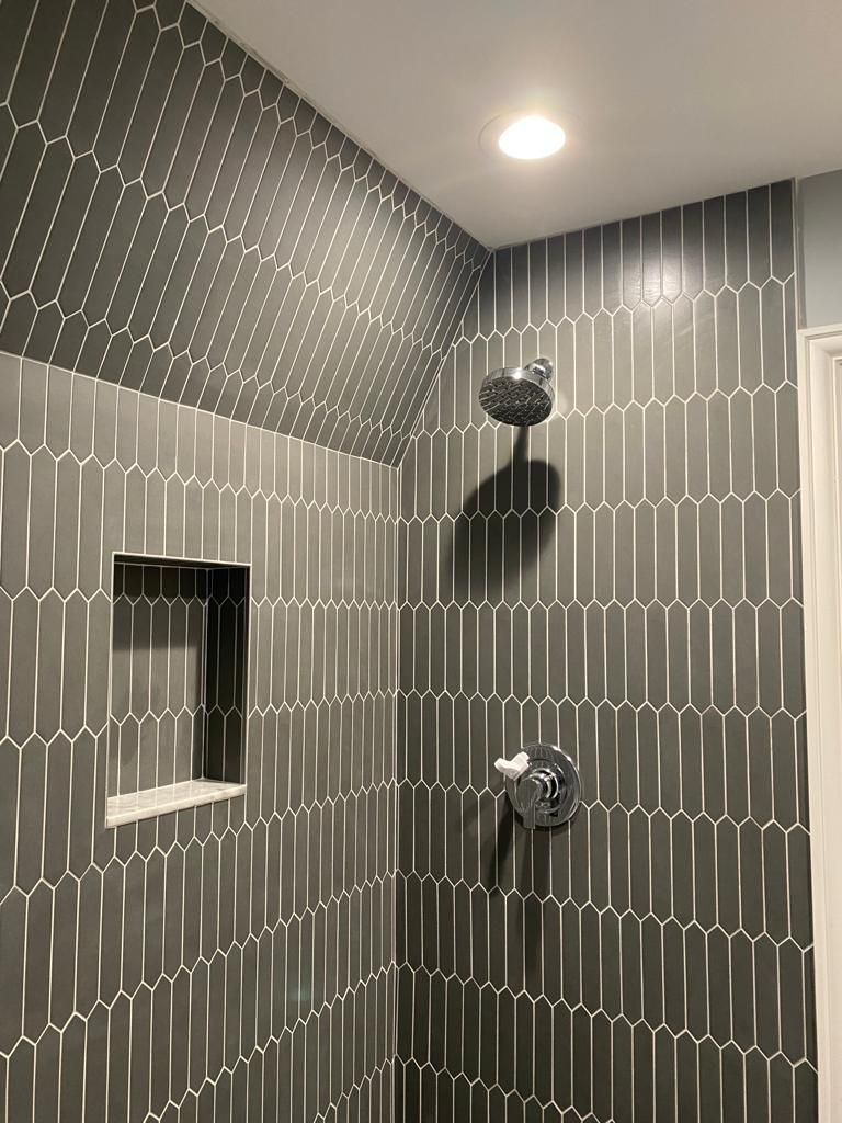 A shower with black tiles and a shower head.