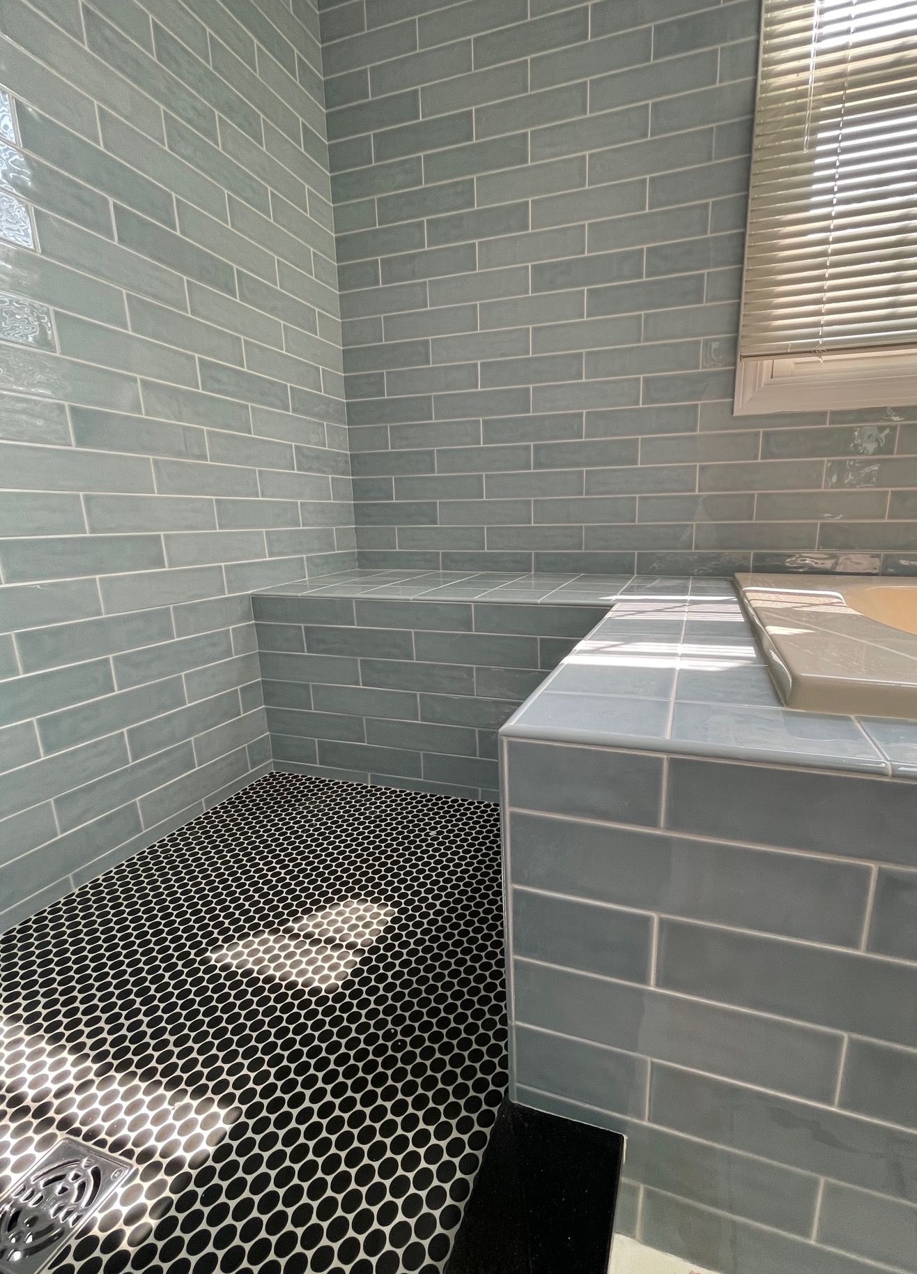 A bathroom with a walk in shower and a window.