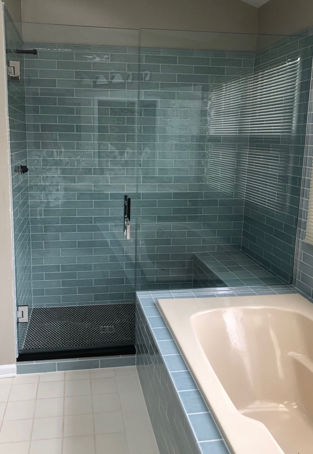 A bathroom with a tub , shower , and blue tiles.