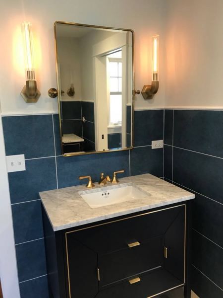 A bathroom with blue tiles and a sink and mirror
