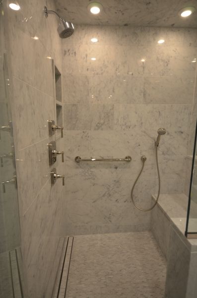 A bathroom with a walk in shower and a bench.