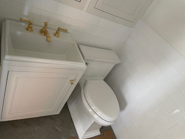 A bathroom with a sink and toilet with gold faucets