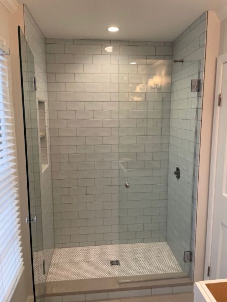 A bathroom with a walk in shower with a glass door