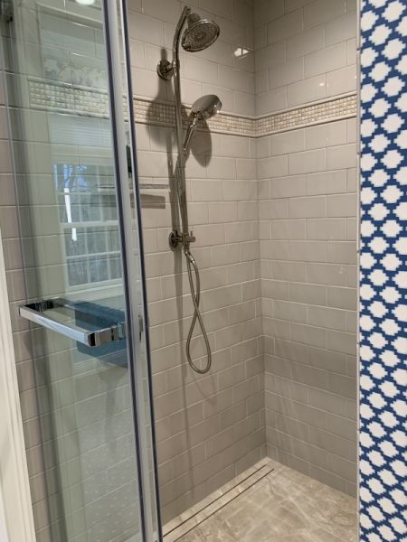A bathroom with a walk in shower with a glass door and a shower head.