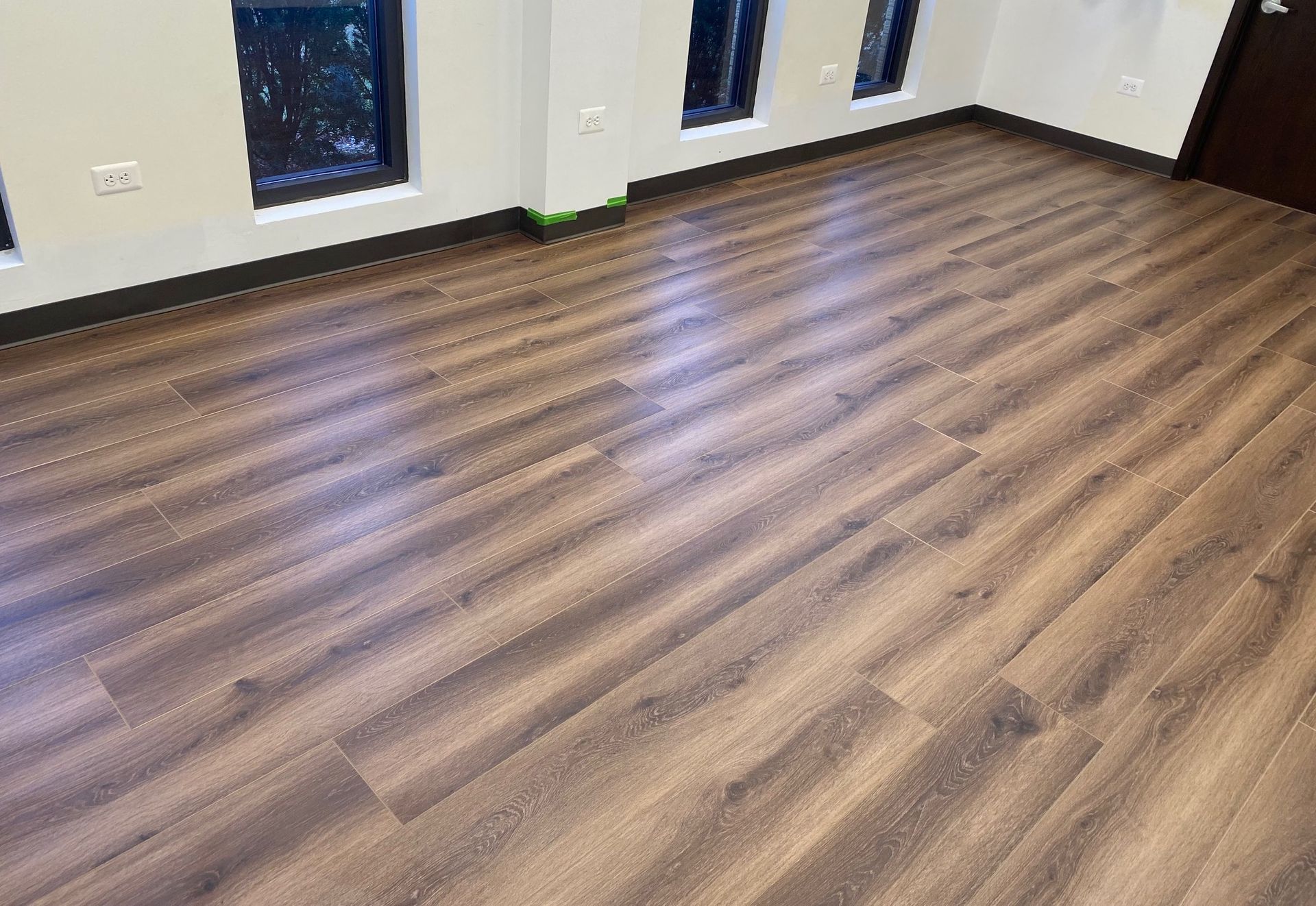 A room with a wooden floor and two windows.