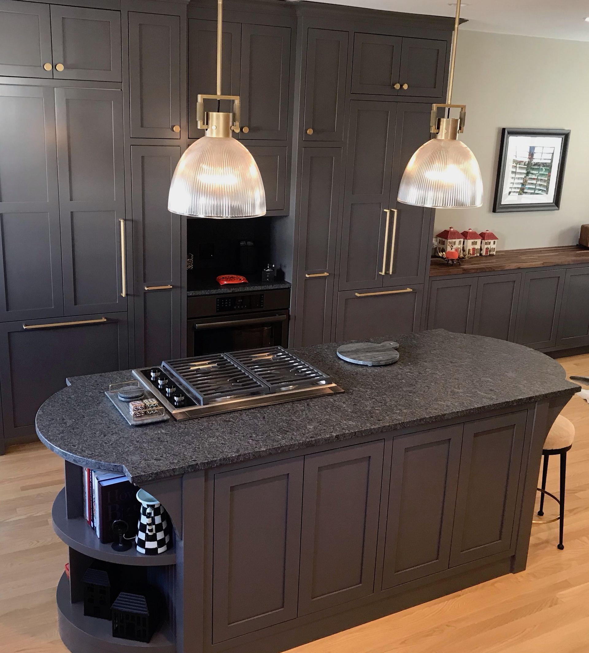 A kitchen with black cabinets and a large island with a stove top oven.