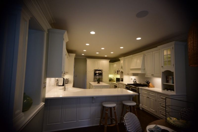 A kitchen with white cabinets and stools and a stove