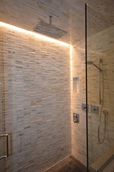 A bathroom with a walk in shower and a brick wall