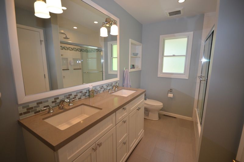 A bathroom with two sinks , a toilet , and a large mirror.