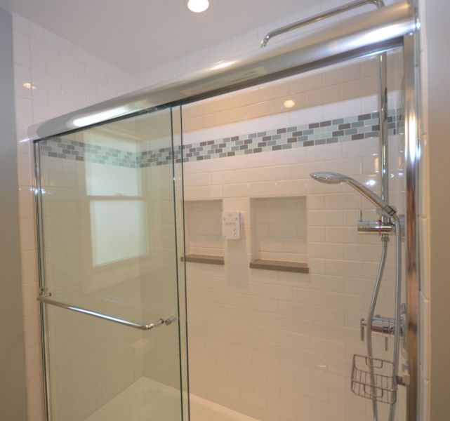 A shower with a sliding glass door and a shower head