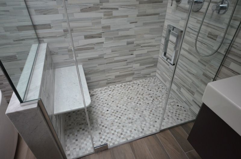 A bathroom with a walk in shower and a bench.