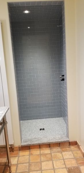 A bathroom with a walk in shower and a tiled floor.