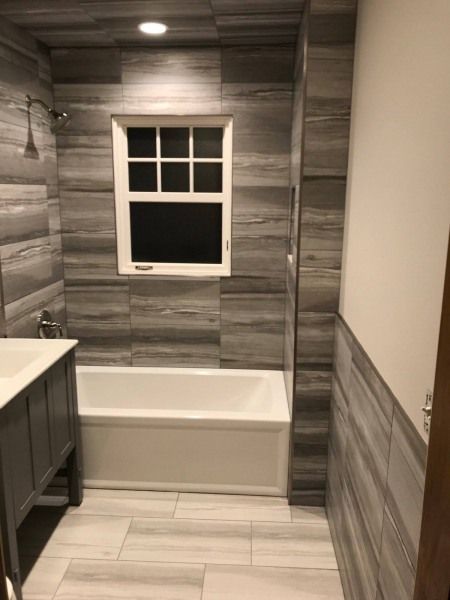A bathroom with a tub , sink , and window.