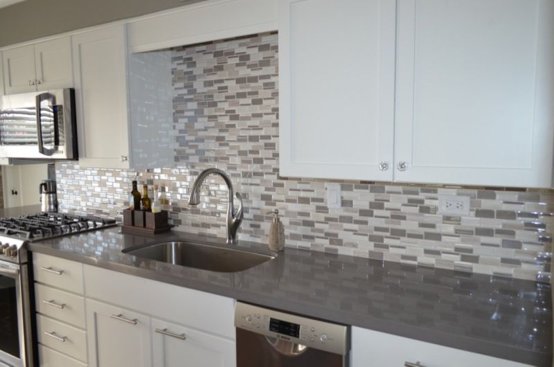 A kitchen with white cabinets , stainless steel appliances , a sink , and a microwave.