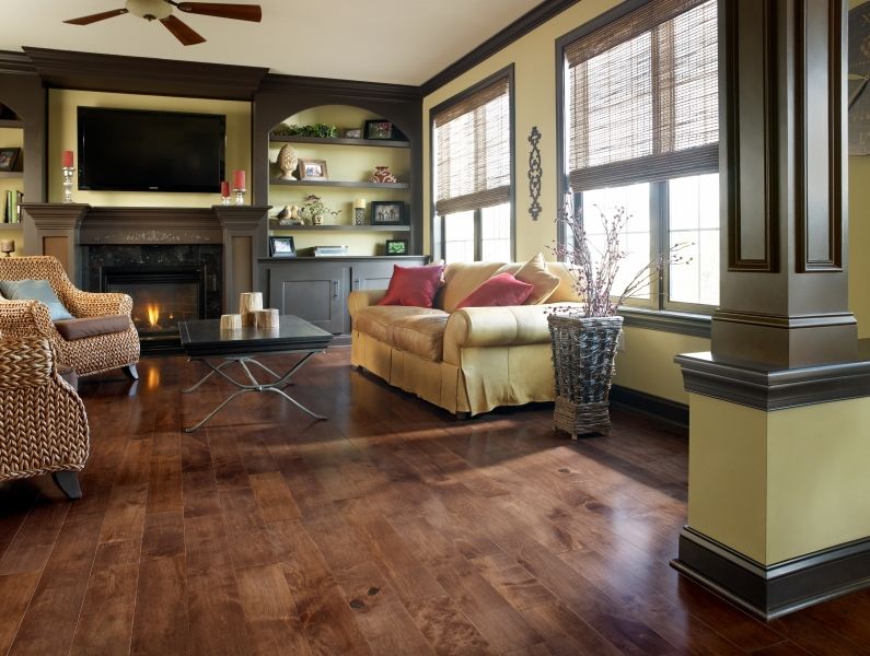 A living room with hardwood floors , a couch , chairs , and a fireplace.