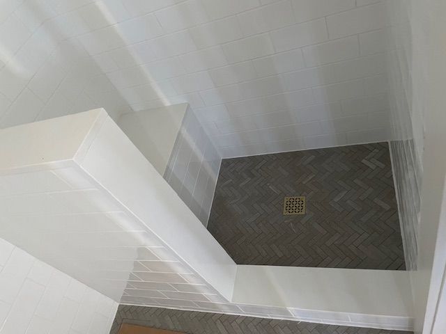 A bathroom with a walk in shower and a drain.