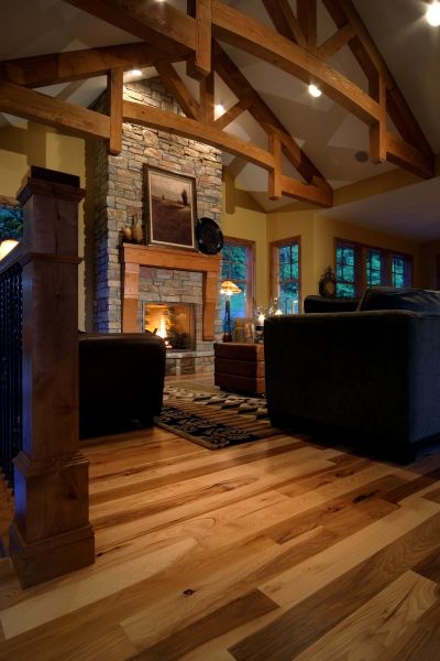 A living room with hardwood floors and a stone fireplace