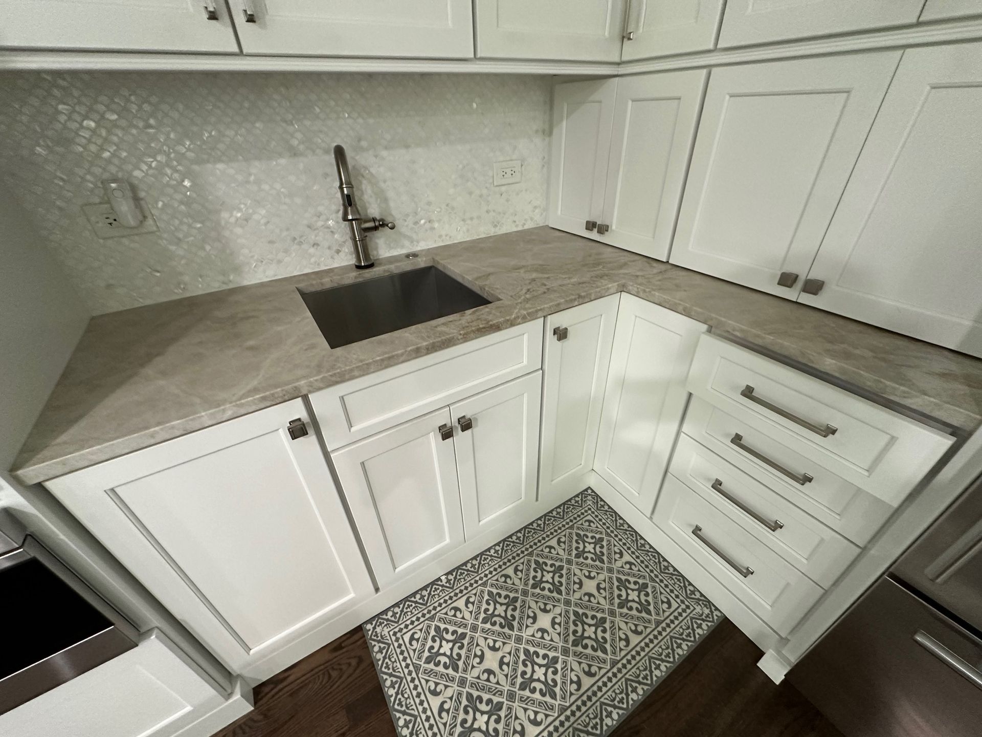 A kitchen with white cabinets and a stainless steel sink