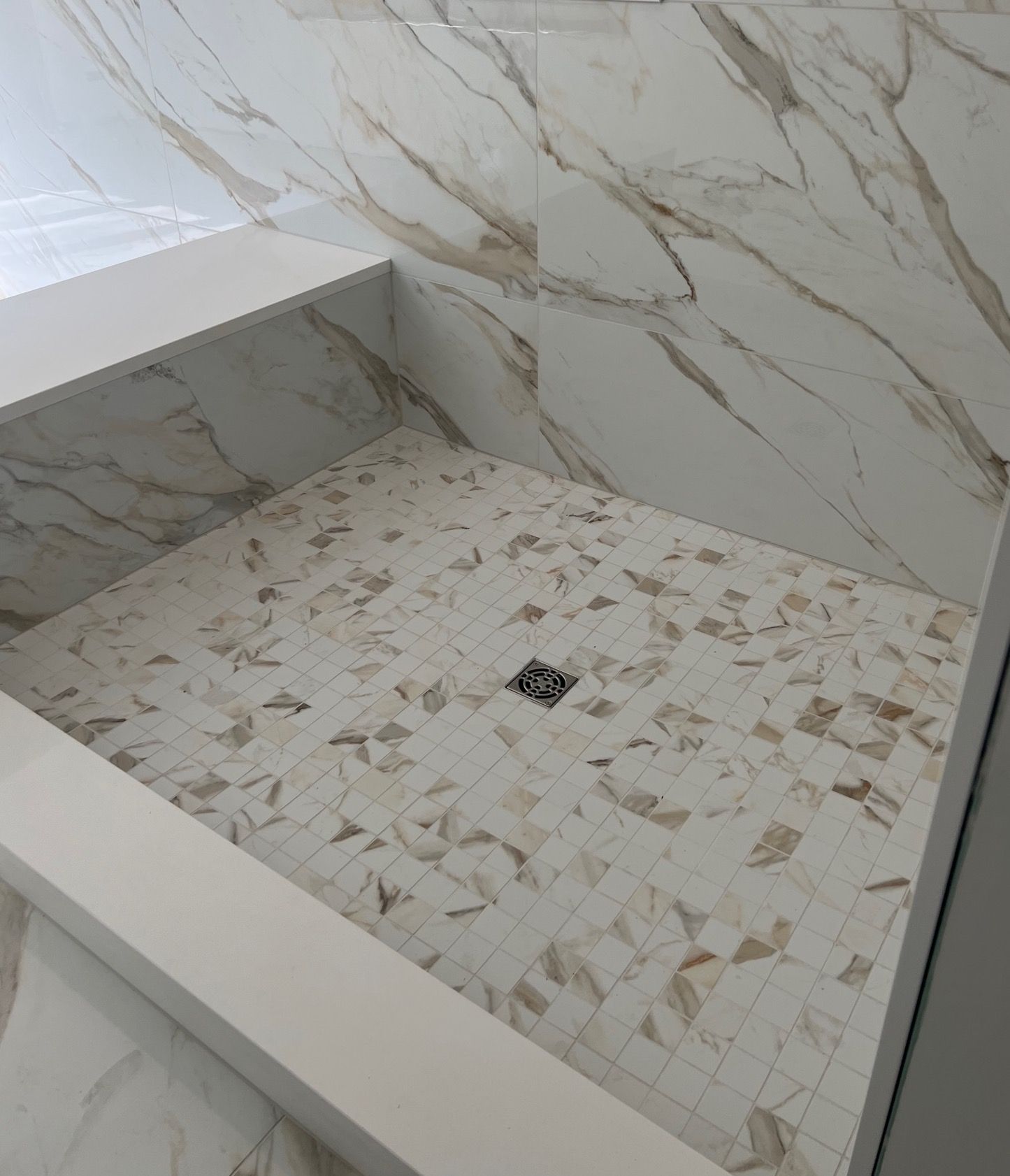 A bathroom with marble tiles and a walk in shower