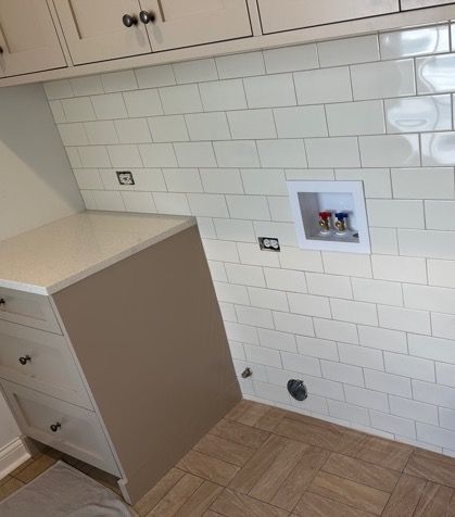 A laundry room with white subway tiles and a washer and dryer.