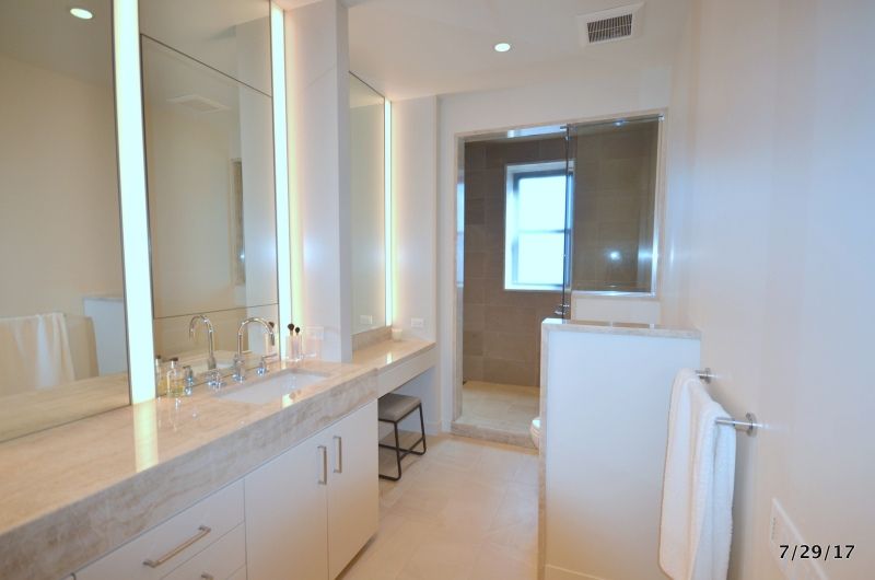 A bathroom with two sinks , two mirrors and a window.