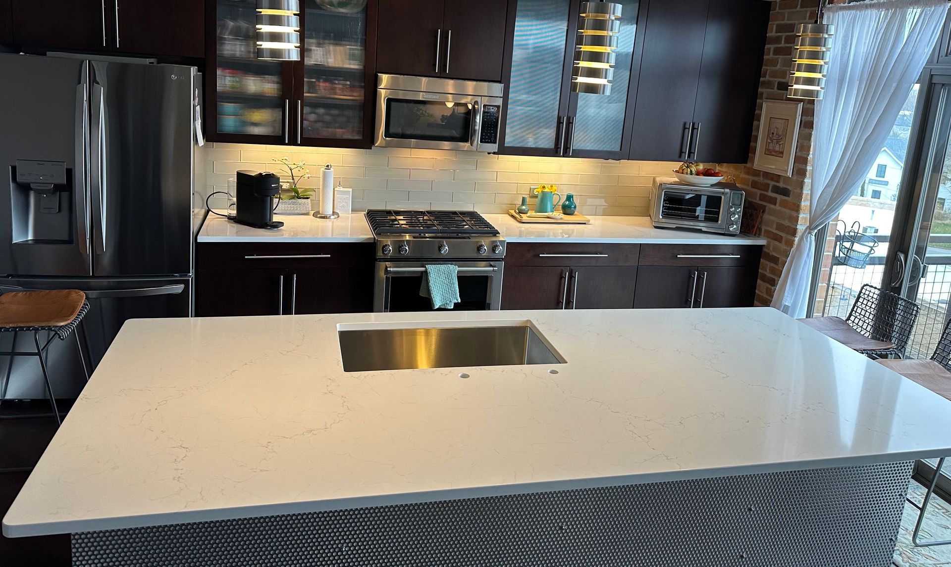 A kitchen with stainless steel appliances and a large island in the middle.
