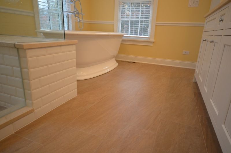 A bathroom with a tub , sink , and window.
