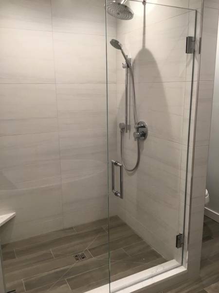 A walk in shower with a glass door and a shower head.